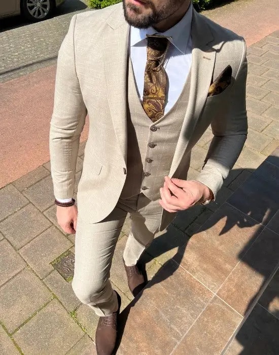 Homme en costume beige élégant avec cravate et pochette.