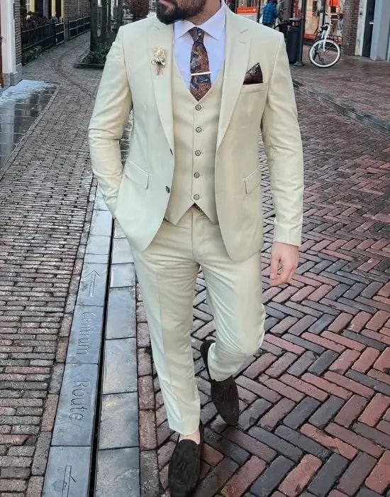 Homme en costume crème avec gilet et cravate élégante