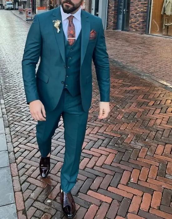 Homme en costume bleu pétrole avec cravate rouge