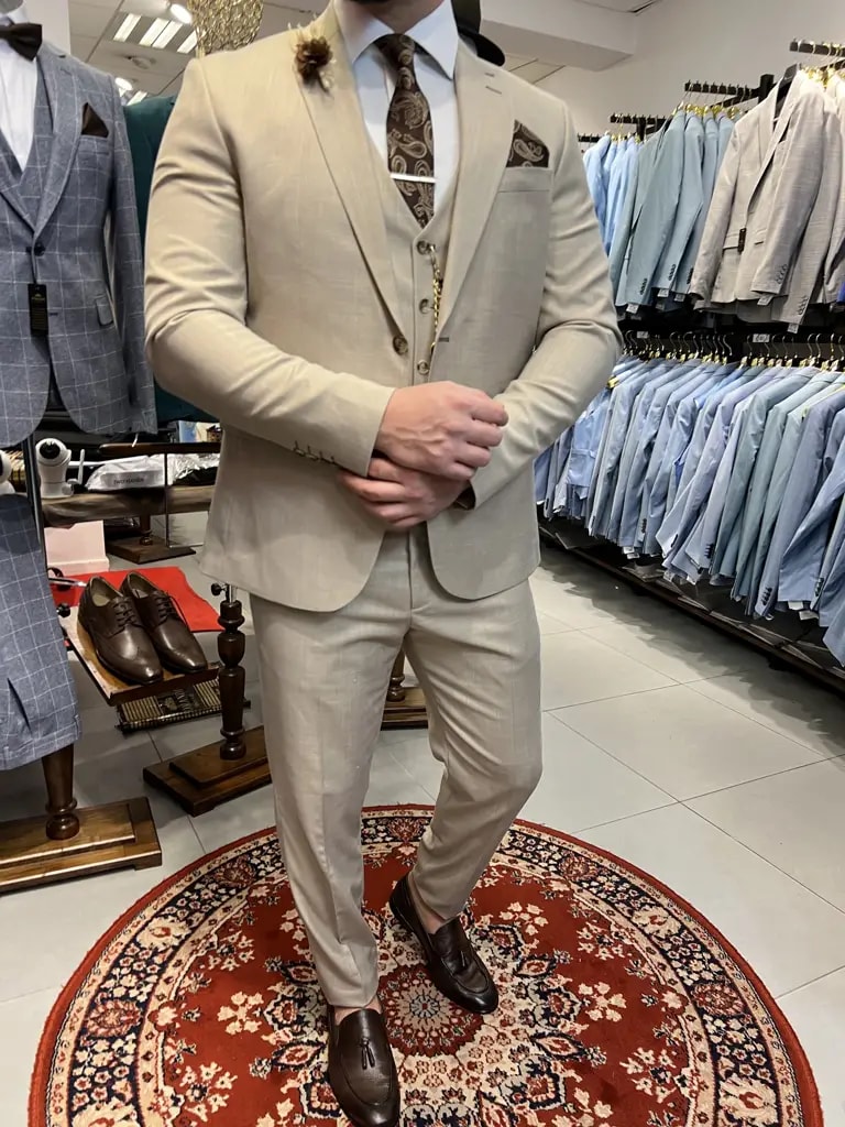 Stijlvol beige pak met bruine accessoires in herenkledingwinkel